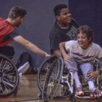 Two Rugby Wheelchair athletes one younger and one older locked in a game of tag